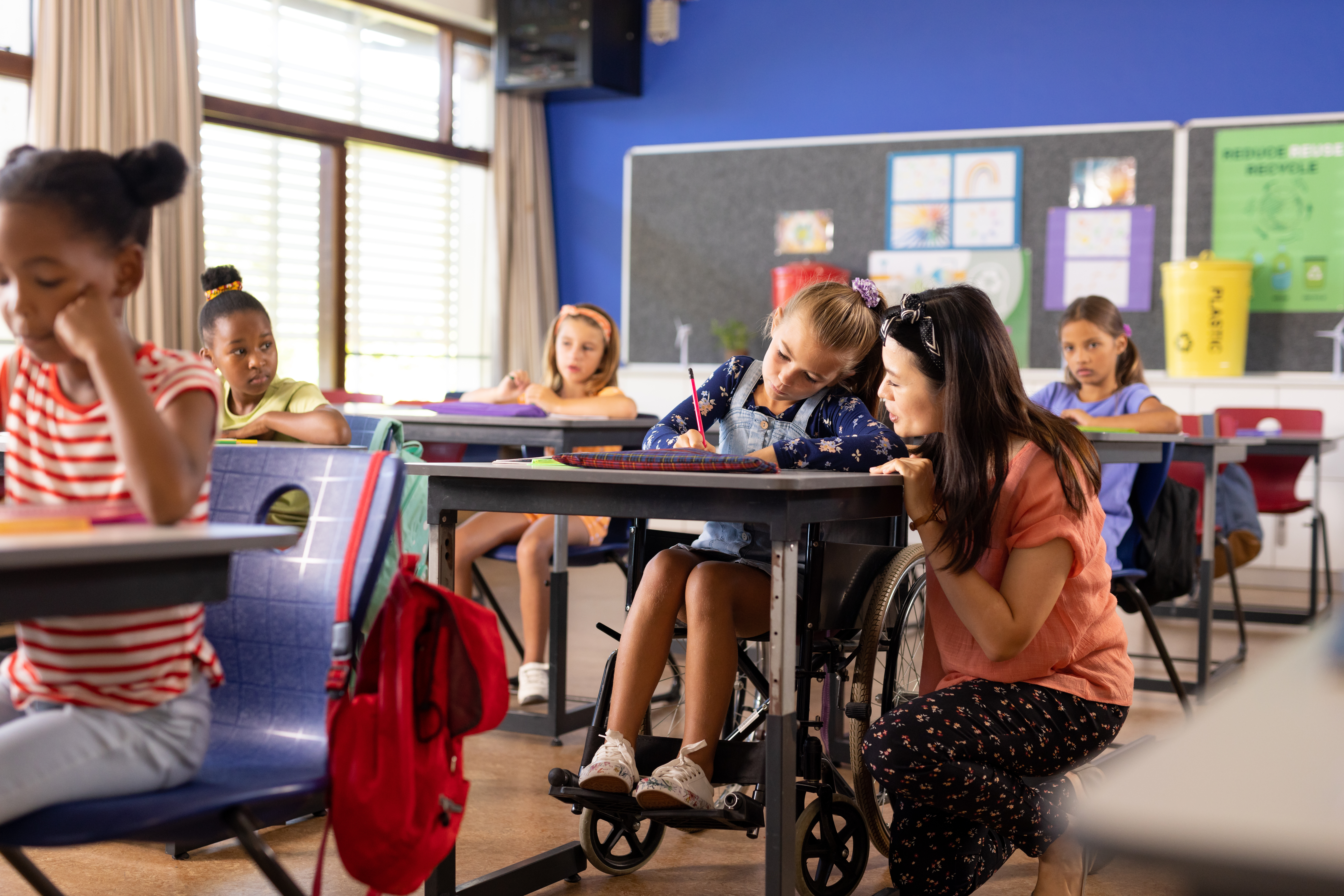 girl doing work with teacher at desk