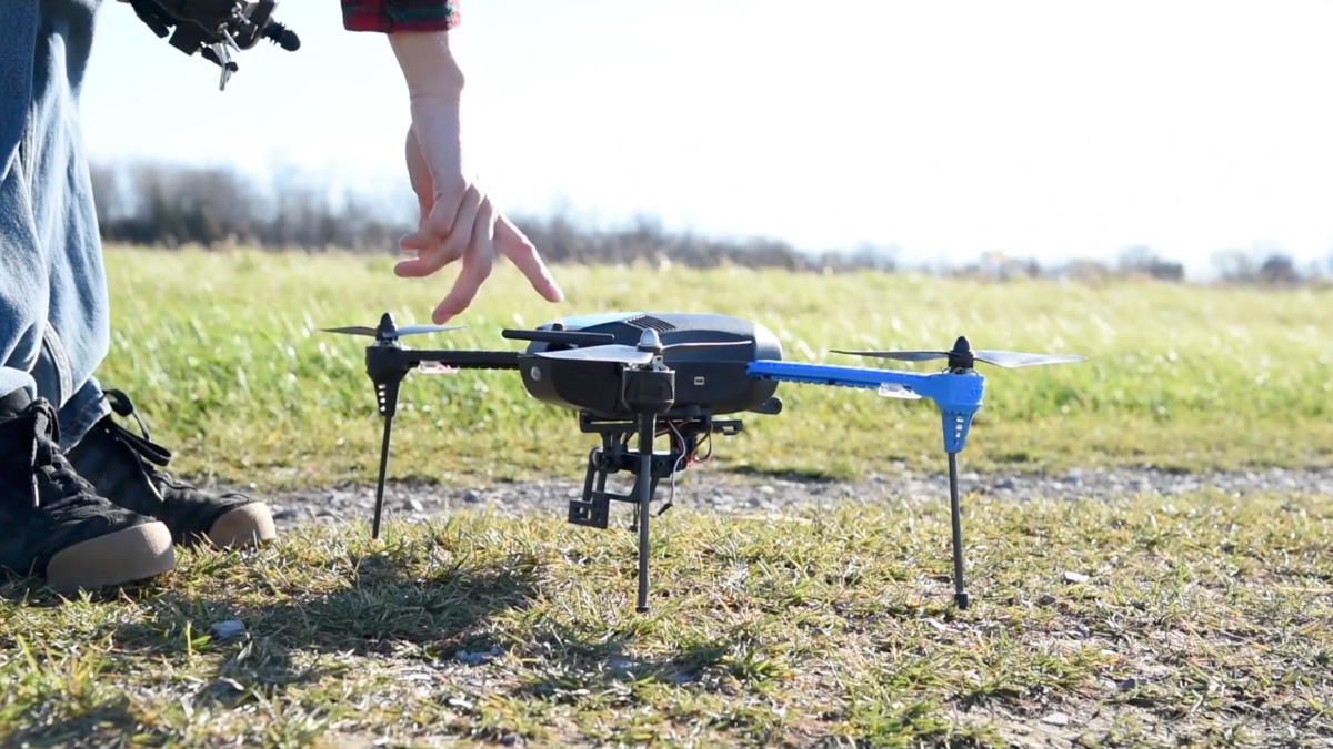 Drone operator staging drone on field.