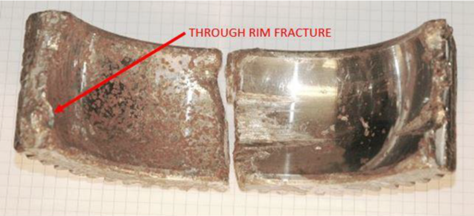 The two segments of the fractured second-stage planet gear recovered. The fatigue fracture through the rim (through-thickness fracture) indicated by red arrow is pointing.