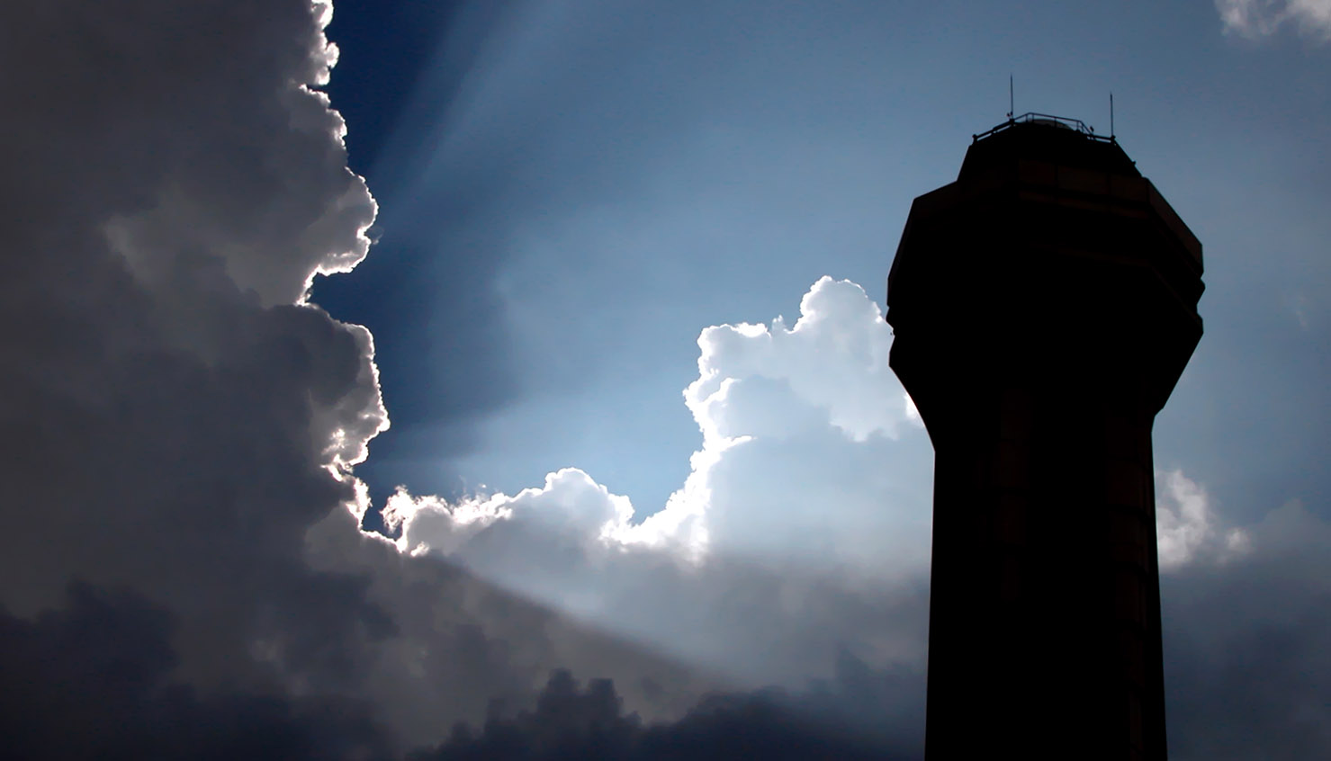 Tower silhouetted by sunlight through clouds