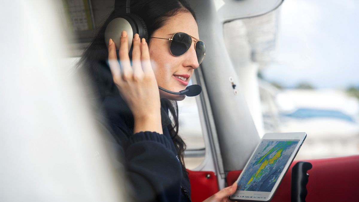 A pilot with a tablet looking at the weather.