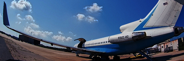 Photo of an regional jet airplane on a runway in front of a small building.