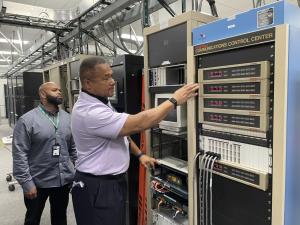 Two workers inspect communications equipment