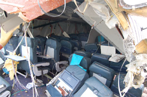 "The left foreground shows an example of post accident deformed floor. The 16g seat rule requires that the seats and seat floor attachments accommodate this type of deformation without breaking loose during the 16g test. Photo from accident investigation."