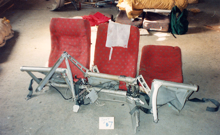 "Collapsed AV052 economy class seat. Note the seat frame is completely fractured in multiple locations and the seat detached from airplane floor due to seat leg failures. Photo from NTSB/FAA investigation."