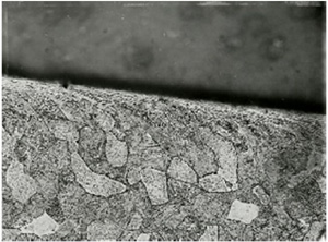 "Magnified view of grain structure at edge of tierod hole. Normal grain structure is present away from hole with distorted grain structure located at the hole edge."