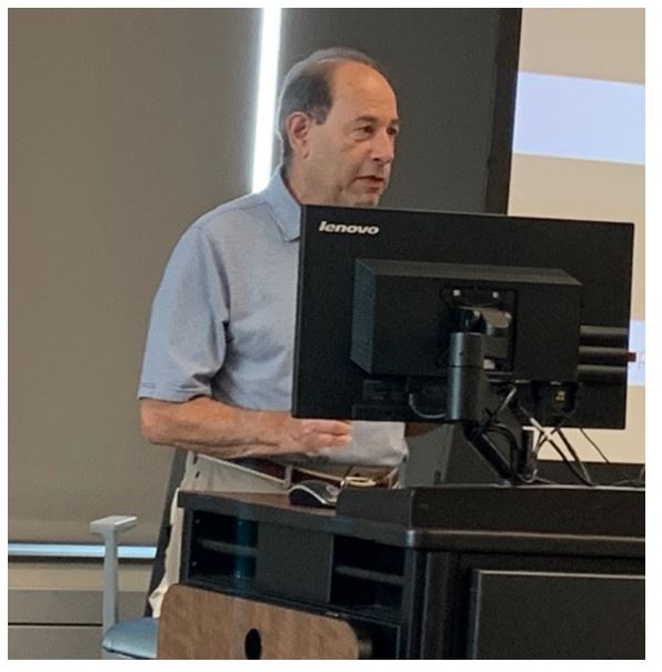 "Man speaking in front of a computer screen"