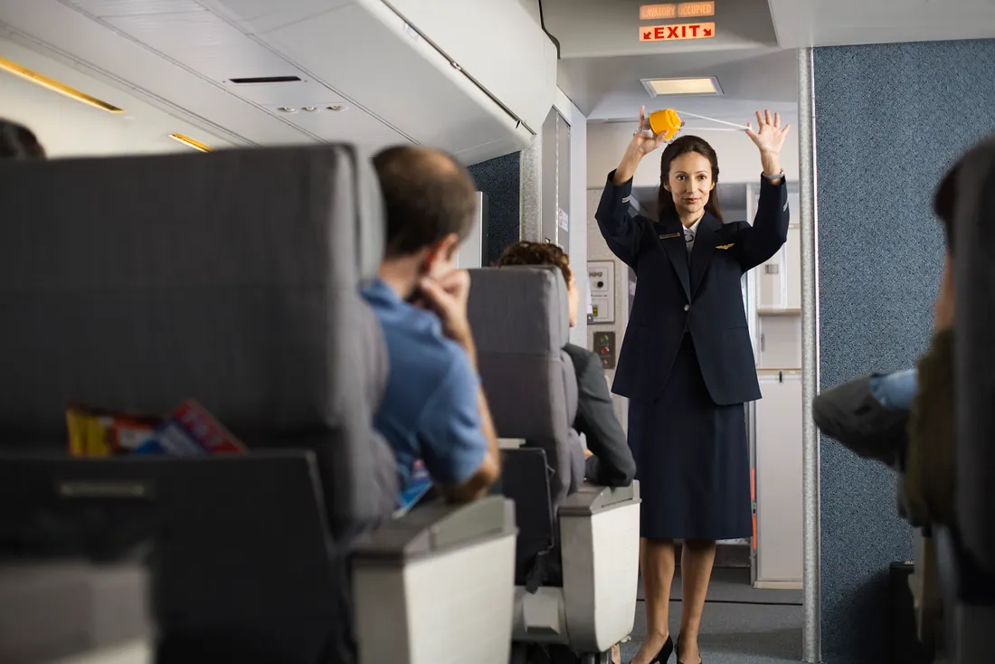 A flight attendant explains safety procedures to passengers on an airplane. (Photo: Getty)