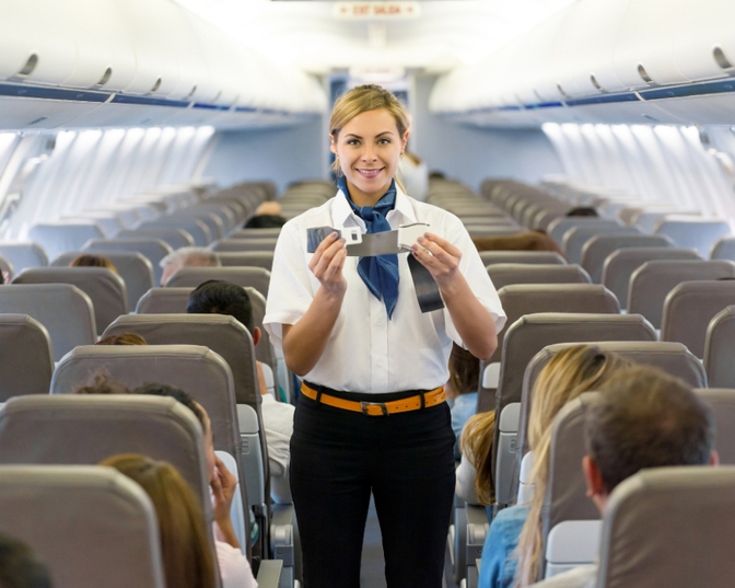 A flight attendant giving a safety demo for passengers
