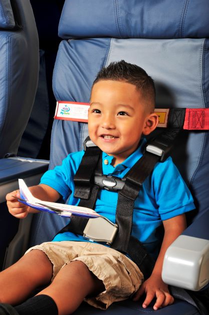 boy in playing with toy plane while in child restraint system on an airplane