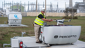 Man with safety vest and hardhat touching the arm of a drone on a platform