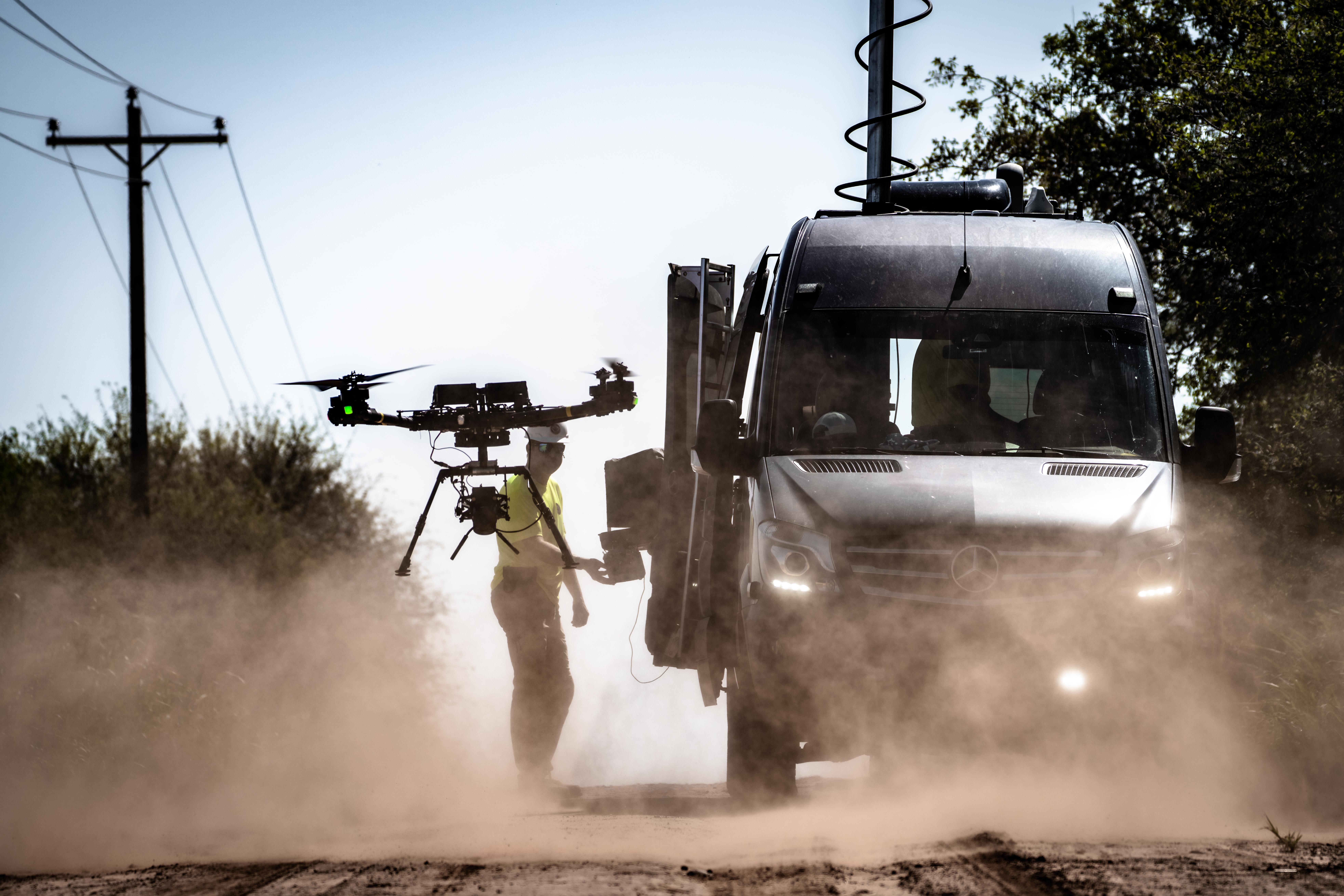 Drone flying in front of van with man in background