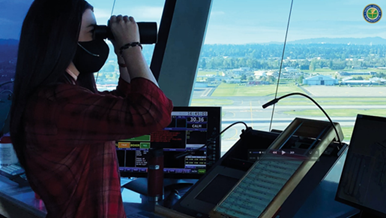 Air traffic controller in tower cab with binoculars