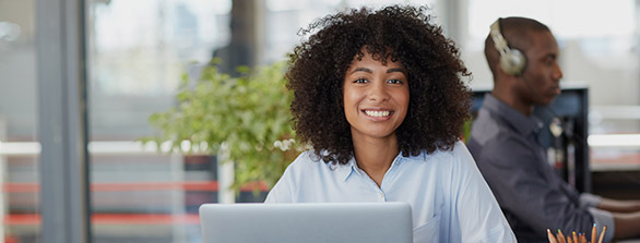 woman smiling from behind a laptop computer
