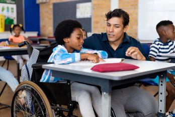 little boy at desk with teacher