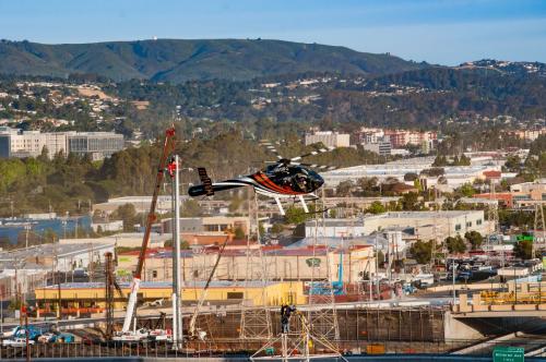 Helicopter flies over town with mountains in background