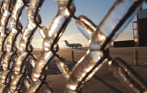 ice on fence with plane in background