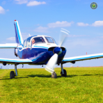 Blue and white GA aircraft on grass with blue sky in background