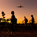 people on bikes watching a plane fly overhead